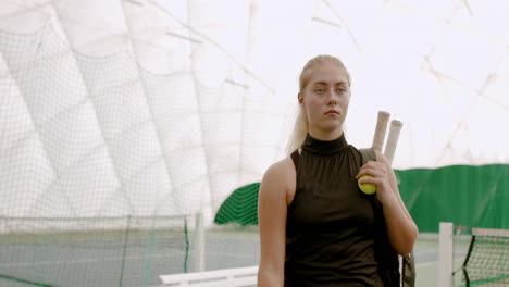 TRACKING-Young-Caucasian-female-tennis-player-leaving-the-court,-rackets-in-a-backpack.-4K-UHD-RAW-graded-footage